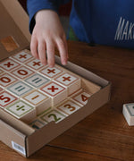 A child reaching for the blocks from the box of Bajo 40 Numbers & Symbols Blocks set. These heirloom quality toys by Bajo are part of a wide range of wooden toys available here at Babipur. 