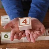 A child holding a number four block from the box of Bajo 40 Numbers & Symbols Blocks set. These heirloom quality toys by Bajo are part of a wide range of wooden toys available here at Babipur. 
