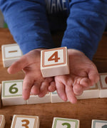 A child holding a number four block from the box of Bajo 40 Numbers & Symbols Blocks set. These heirloom quality toys by Bajo are part of a wide range of wooden toys available here at Babipur. 