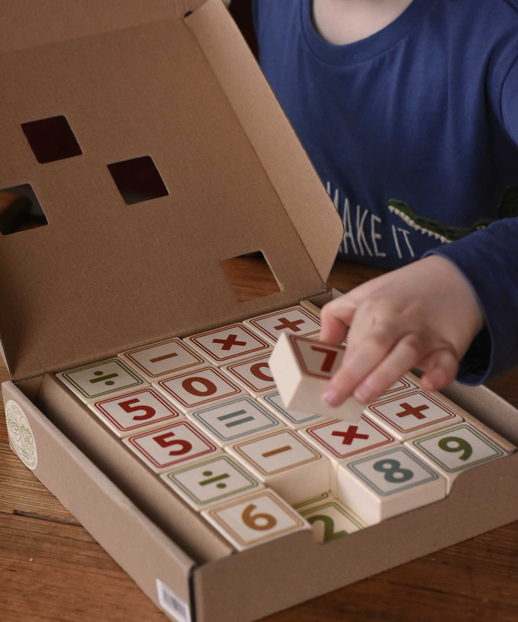 A child taking a block from the box of Bajo 40 Numbers & Symbols Blocks set. These heirloom quality toys by Bajo are part of a wide range of wooden toys available here at Babipur. 