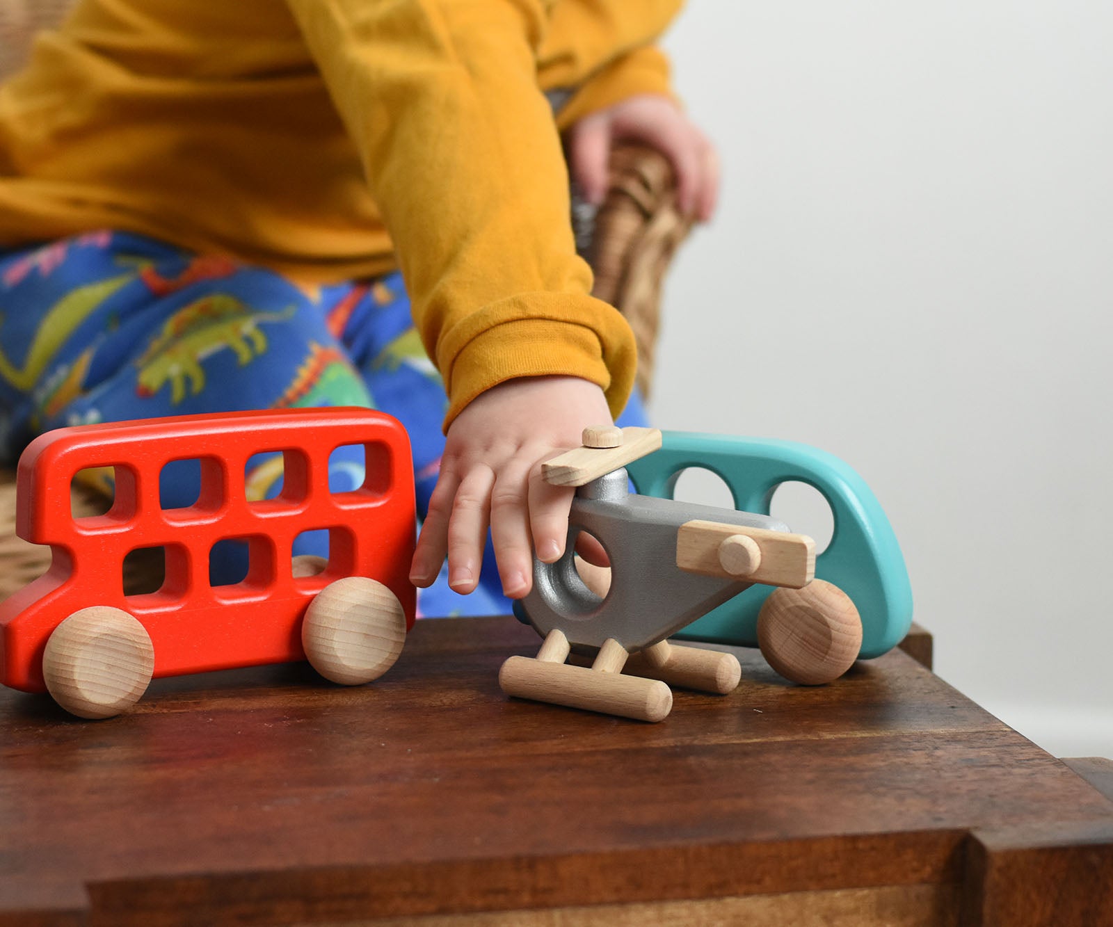 A child reaching for the Bajo Police Helicopter wooden toy. Other Bajo vehicles can be seen in the background. These heirloom quality toys by Bajo are part of a wide range of wooden toys available here at Babipur. 
