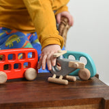 A child reaching for the Bajo Police Helicopter wooden toy. Other Bajo vehicles can be seen in the background. These heirloom quality toys by Bajo are part of a wide range of wooden toys available here at Babipur. 