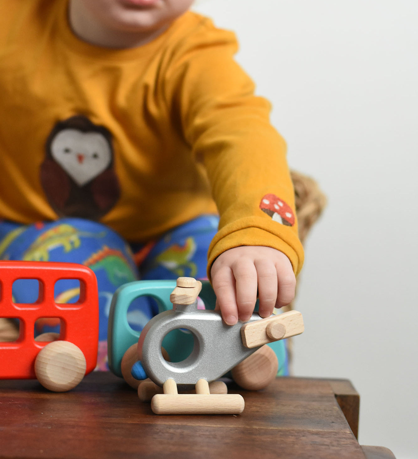 A child reaching for the Bajo Police Helicopter wooden toy. Other Bajo vehicles can be seen in the background. These heirloom quality toys by Bajo are part of a wide range of wooden toys available here at Babipur. 
