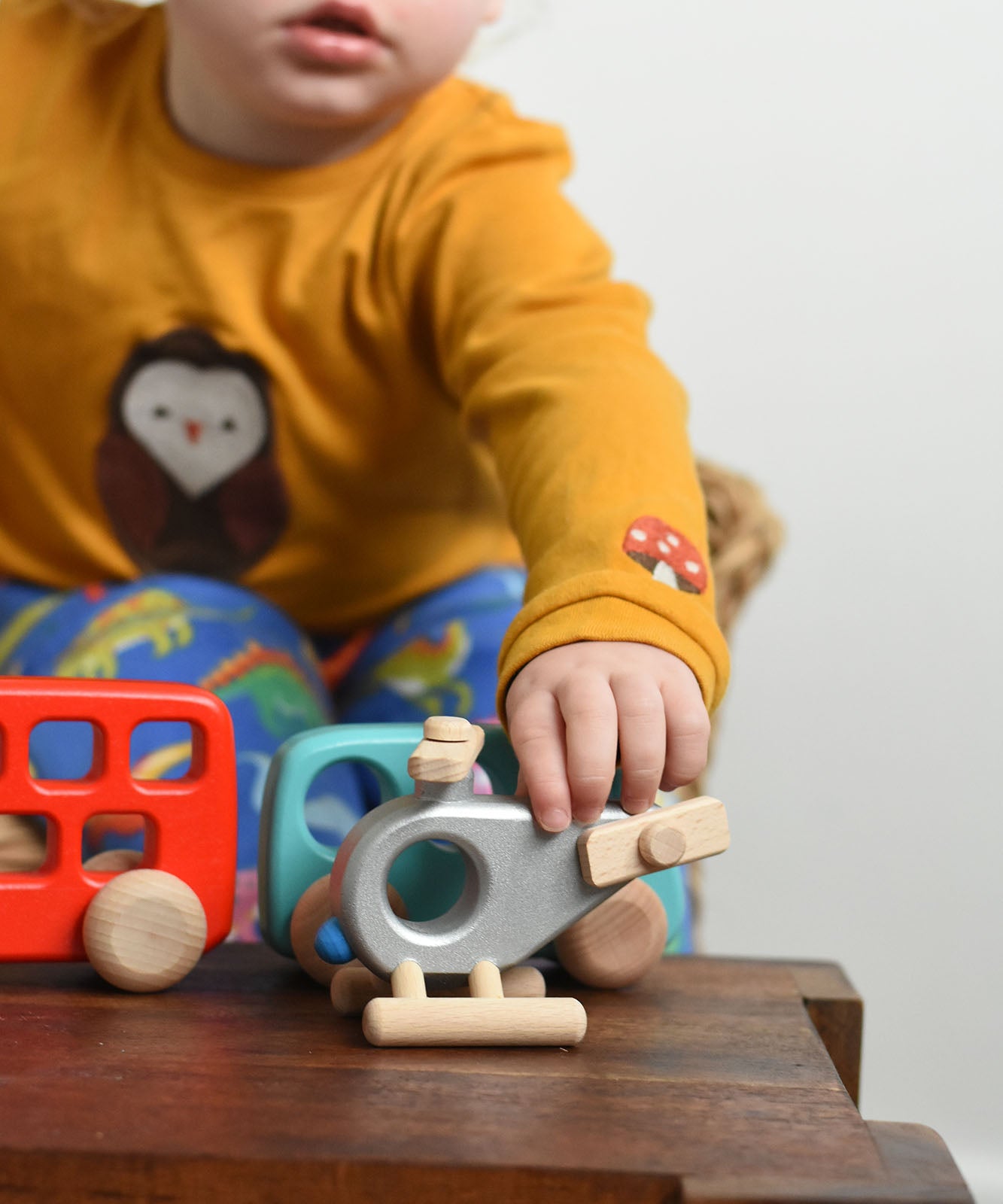 A child reaching for the Bajo Police Helicopter wooden toy. Other Bajo vehicles can be seen in the background. These heirloom quality toys by Bajo are part of a wide range of wooden toys available here at Babipur. 