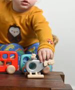 A child reaching for the Bajo Police Helicopter wooden toy. Other Bajo vehicles can be seen in the background. These heirloom quality toys by Bajo are part of a wide range of wooden toys available here at Babipur. 