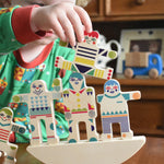 A child playing with the Bajo world balance game. Th echild has stacked 3 pieces on the base and had another in his hand that he is placing on top.