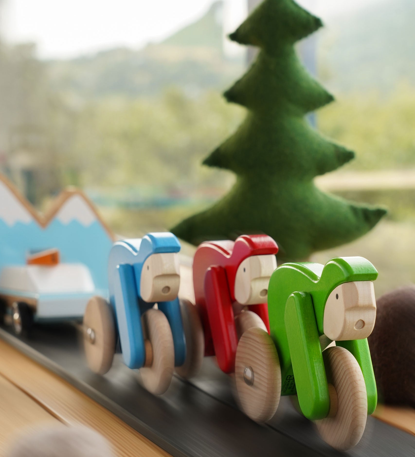 Bajo Velo cyclist toys shown racing along in a small world play scene. This wooden toy is part of a wide range of push along toys available at Babipur.
