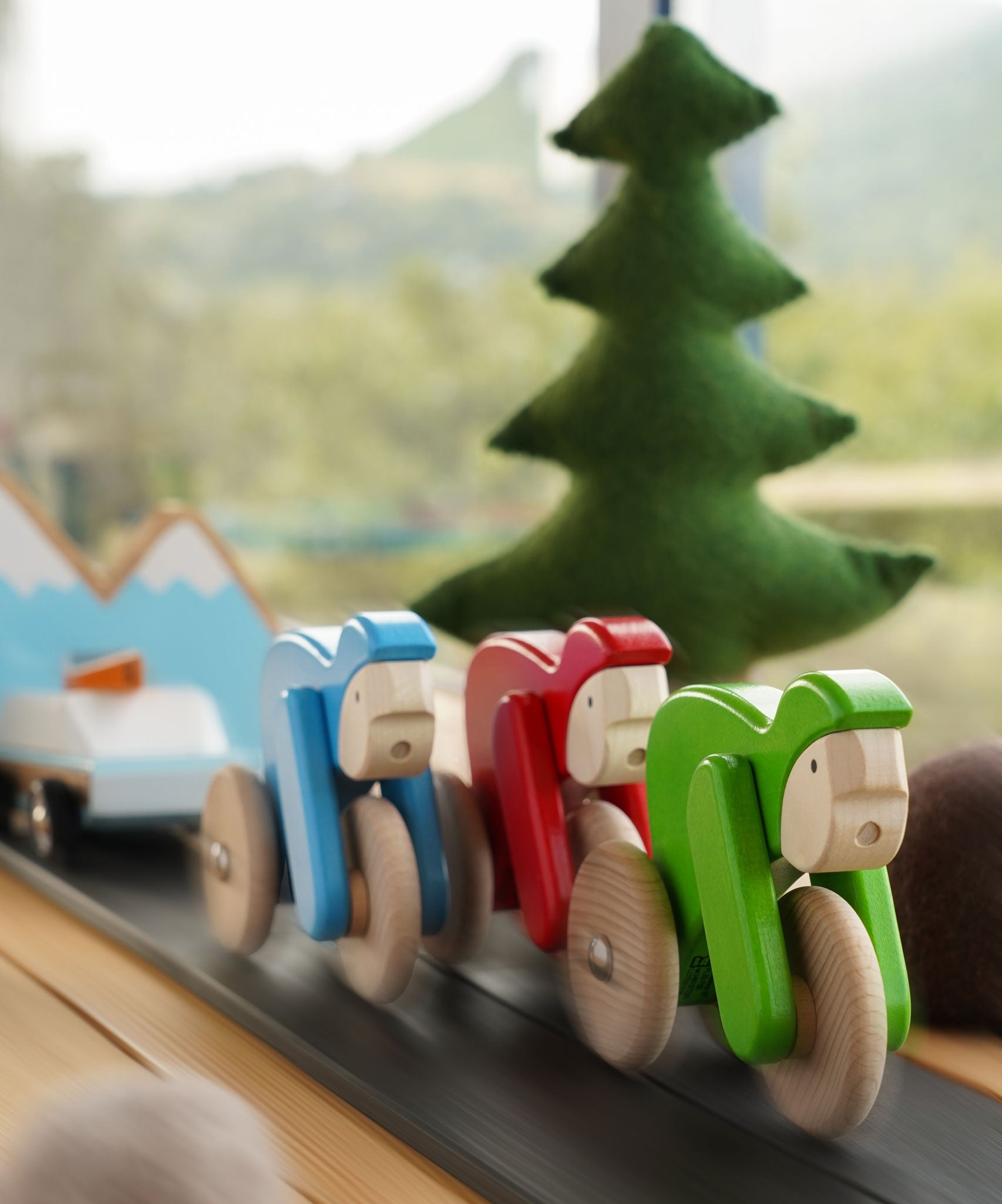 Bajo Velo cyclist toys shown racing along in a small world play scene. This wooden toy is part of a wide range of push along toys available at Babipur.