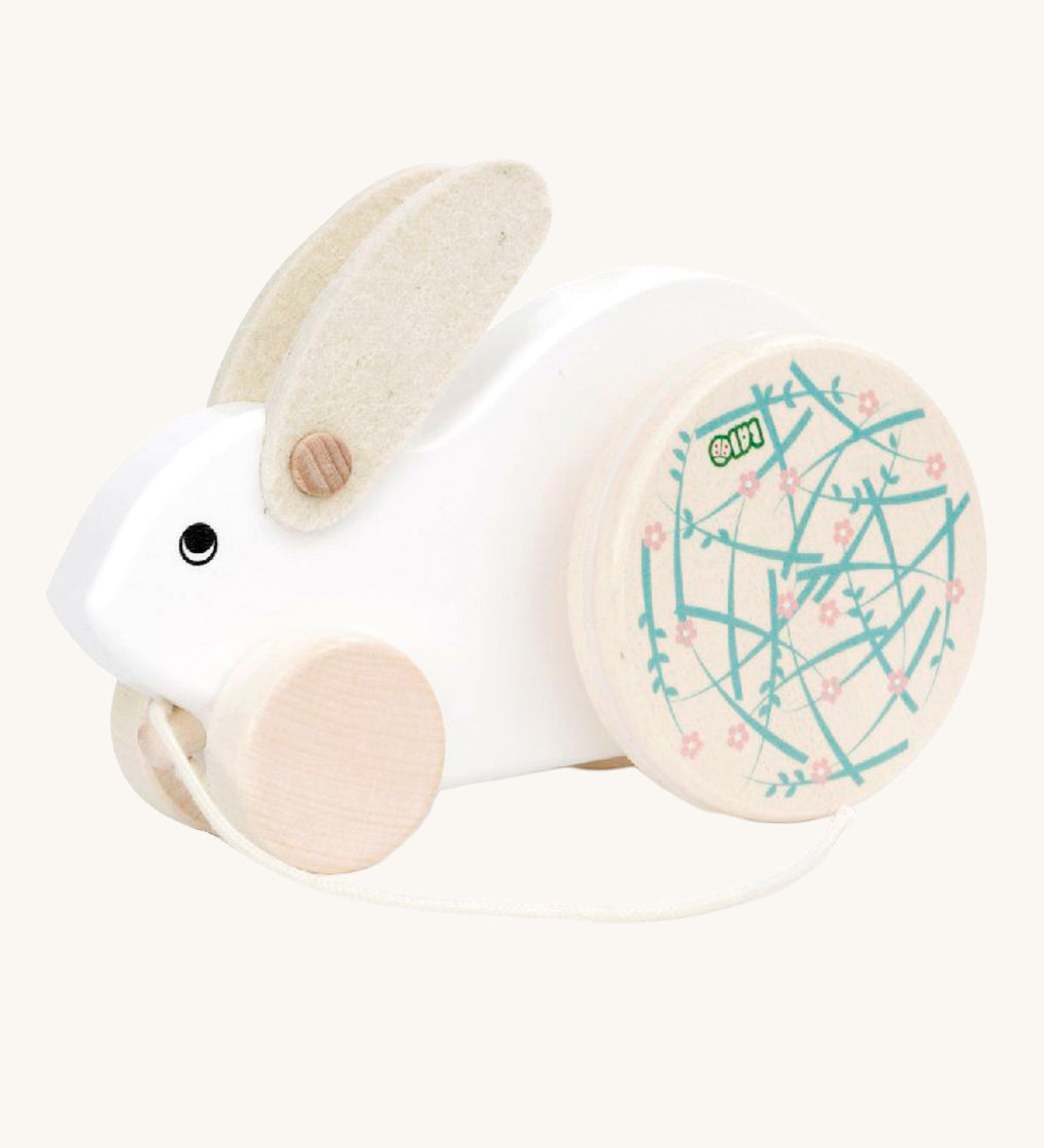 A white Bajo Big Rabbit toy. This pull along wooden toy has small wheels at the front and large decorated wheels at the back. The rabbit makes a jumping motion as it is being pulled along. We have a wide range of Bajo wooden toys available here at Babipur. 