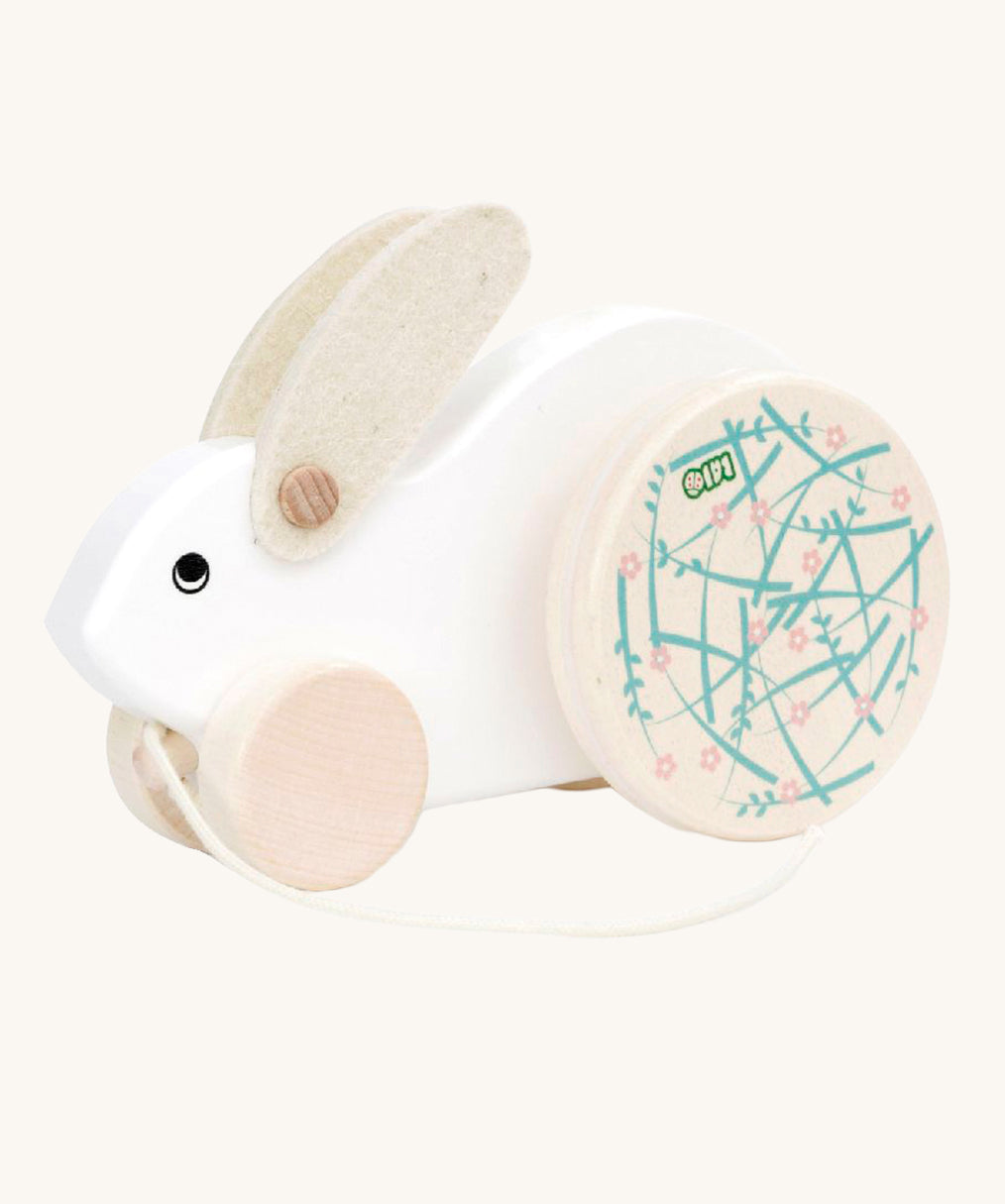 A white Bajo Big Rabbit toy. This pull along wooden toy has small wheels at the front and large decorated wheels at the back. The rabbit makes a jumping motion as it is being pulled along. We have a wide range of Bajo wooden toys available here at Babipur. 