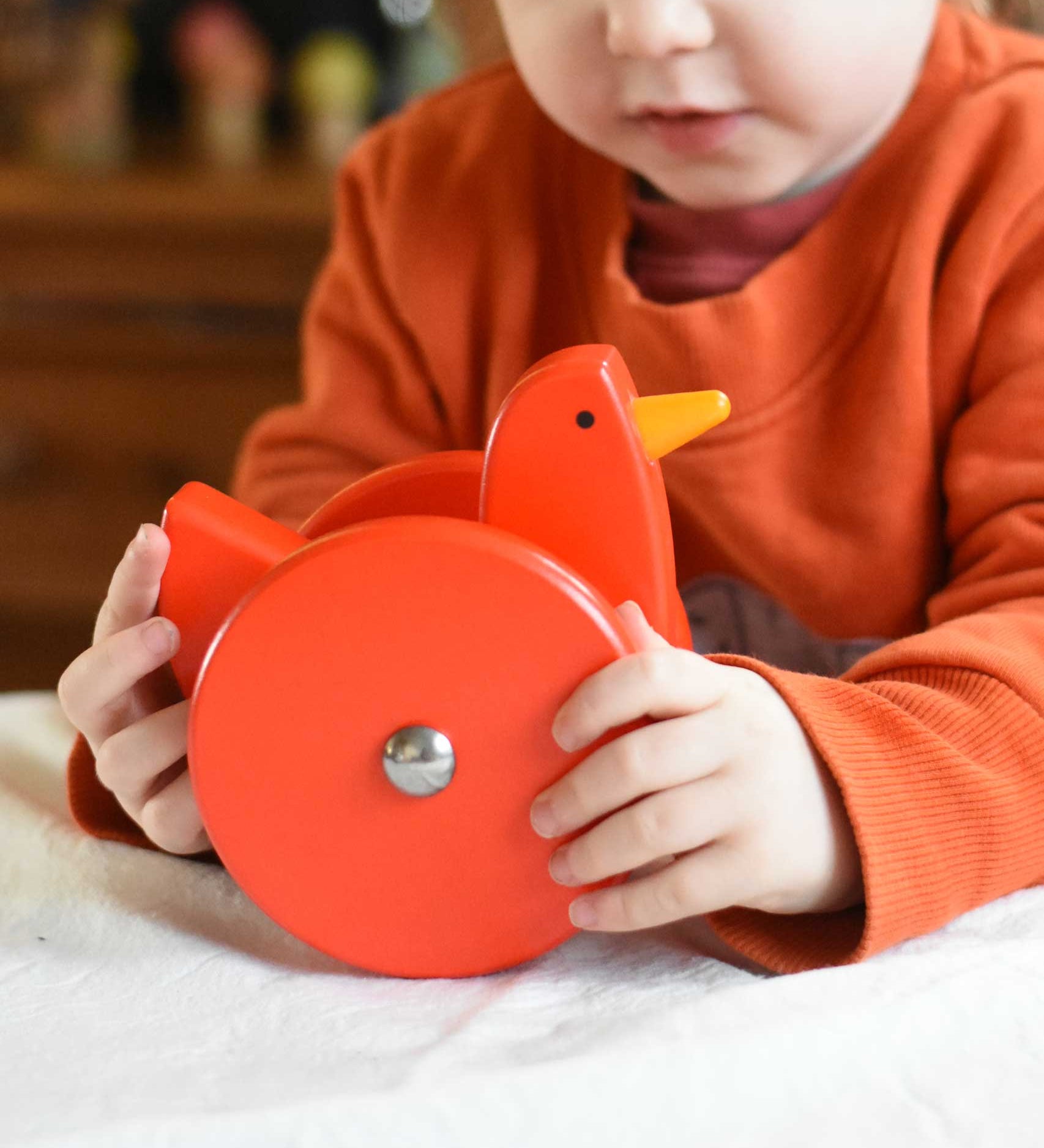 A child playing with the Bajo Red Wobbling Chicken. A red push along wooden chicken toy that bob up and down when pushed along.  These heirloom quality toys by Bajo are part of a wide range of wooden toys available here at Babipur.