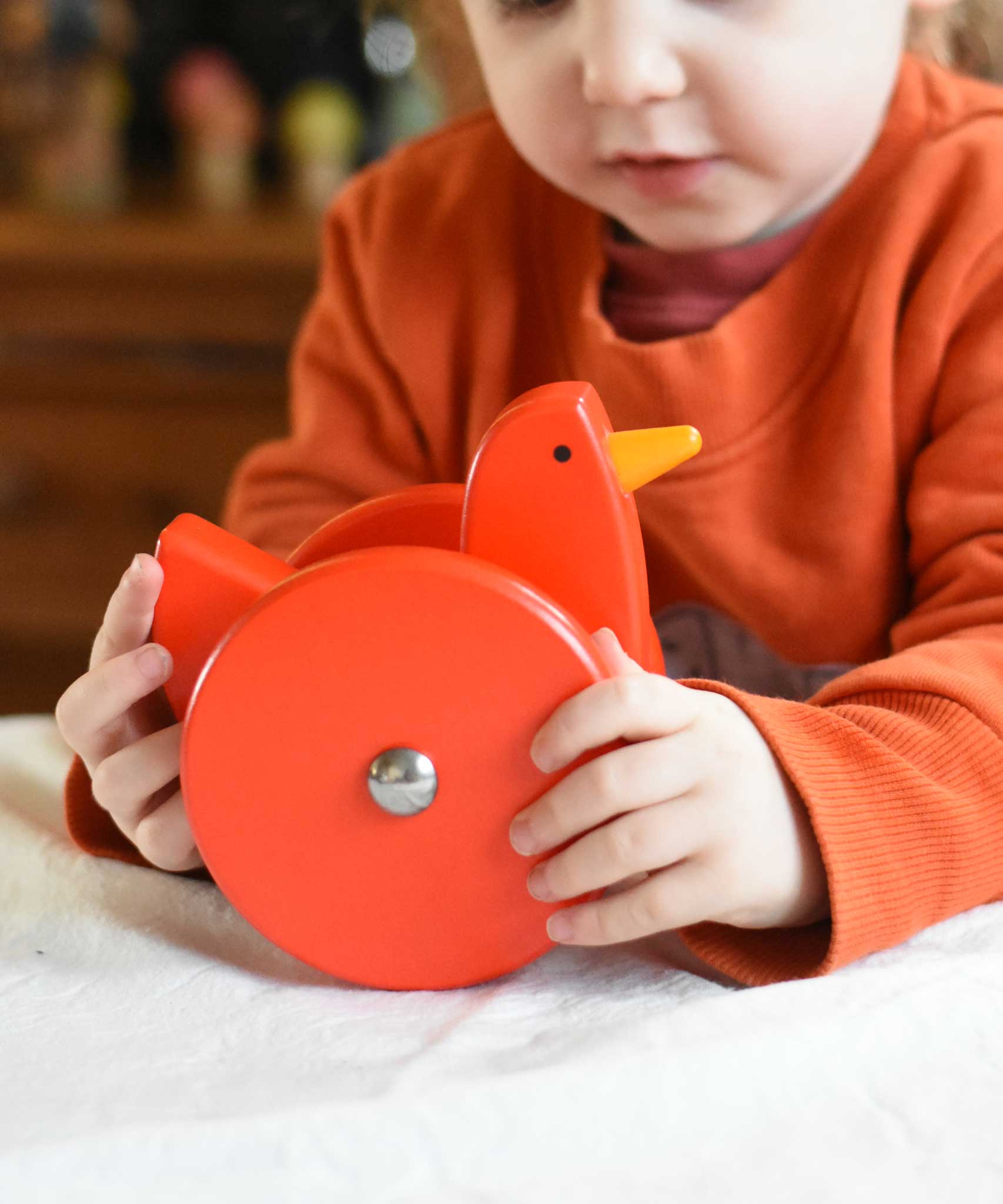 A child playing with the Bajo Red Wobbling Chicken. A red push along wooden chicken toy that bob up and down when pushed along.  These heirloom quality toys by Bajo are part of a wide range of wooden toys available here at Babipur.