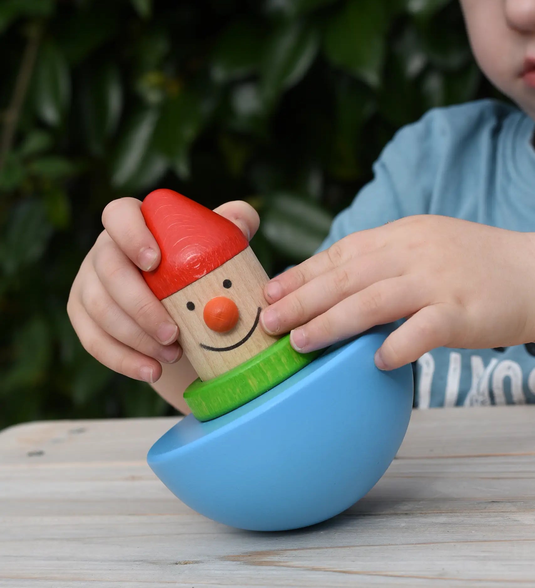 Child playing with Bajo roly poly wobbling dwarf wooden baby toy.