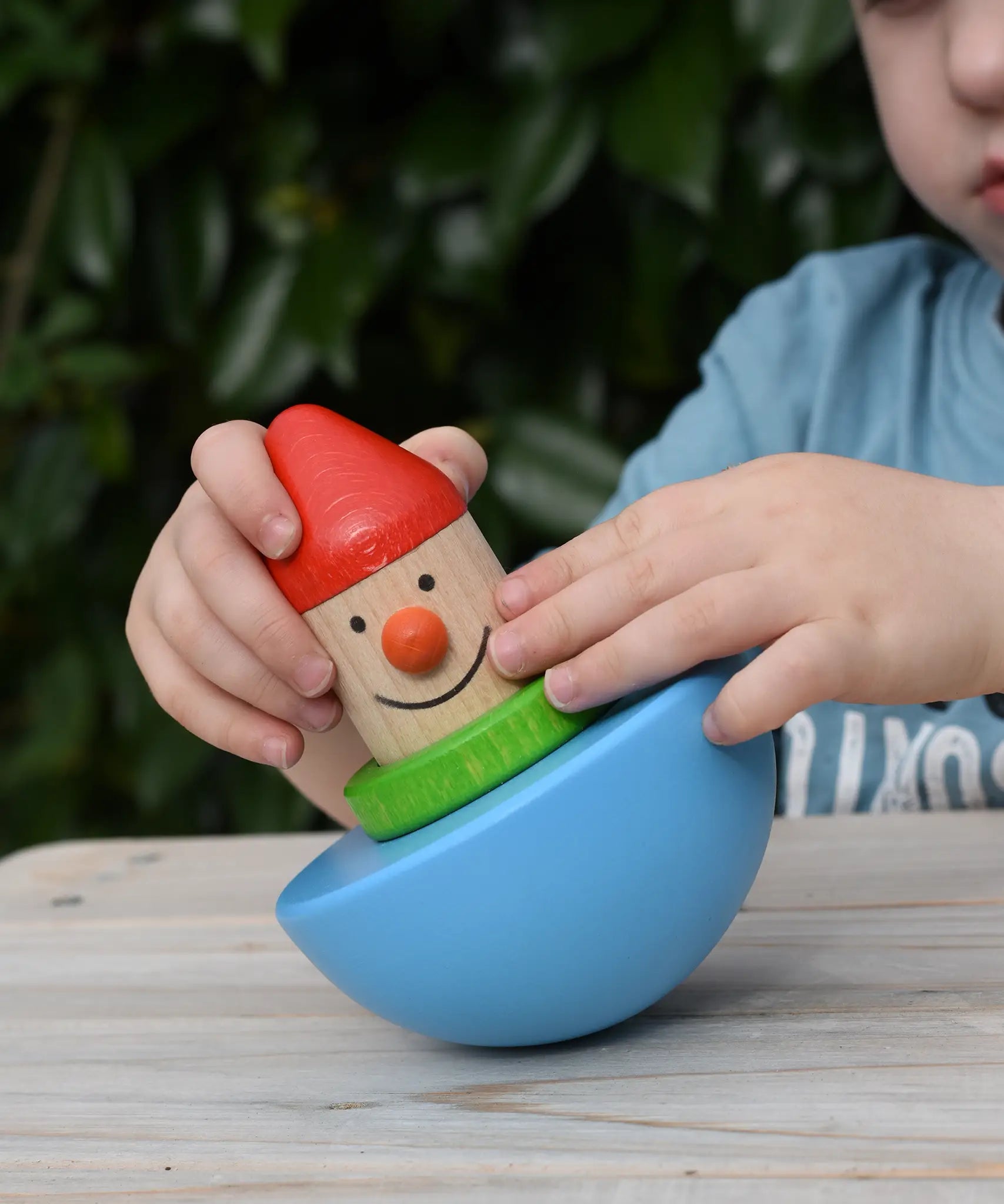 Child playing with Bajo roly poly wobbling dwarf wooden baby toy.