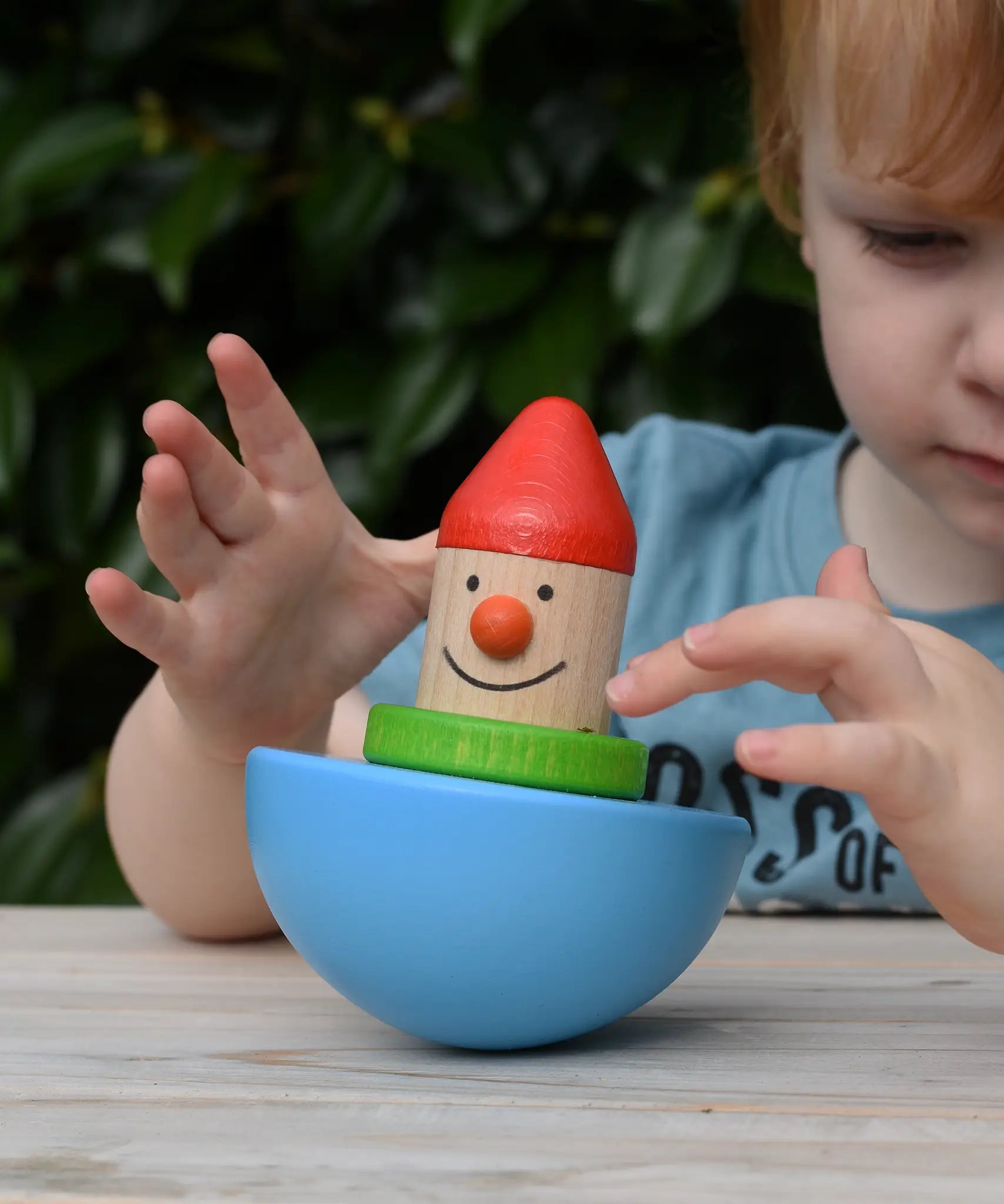 Child playing with Bajo roly poly wobbling dwarf wooden baby toy.
