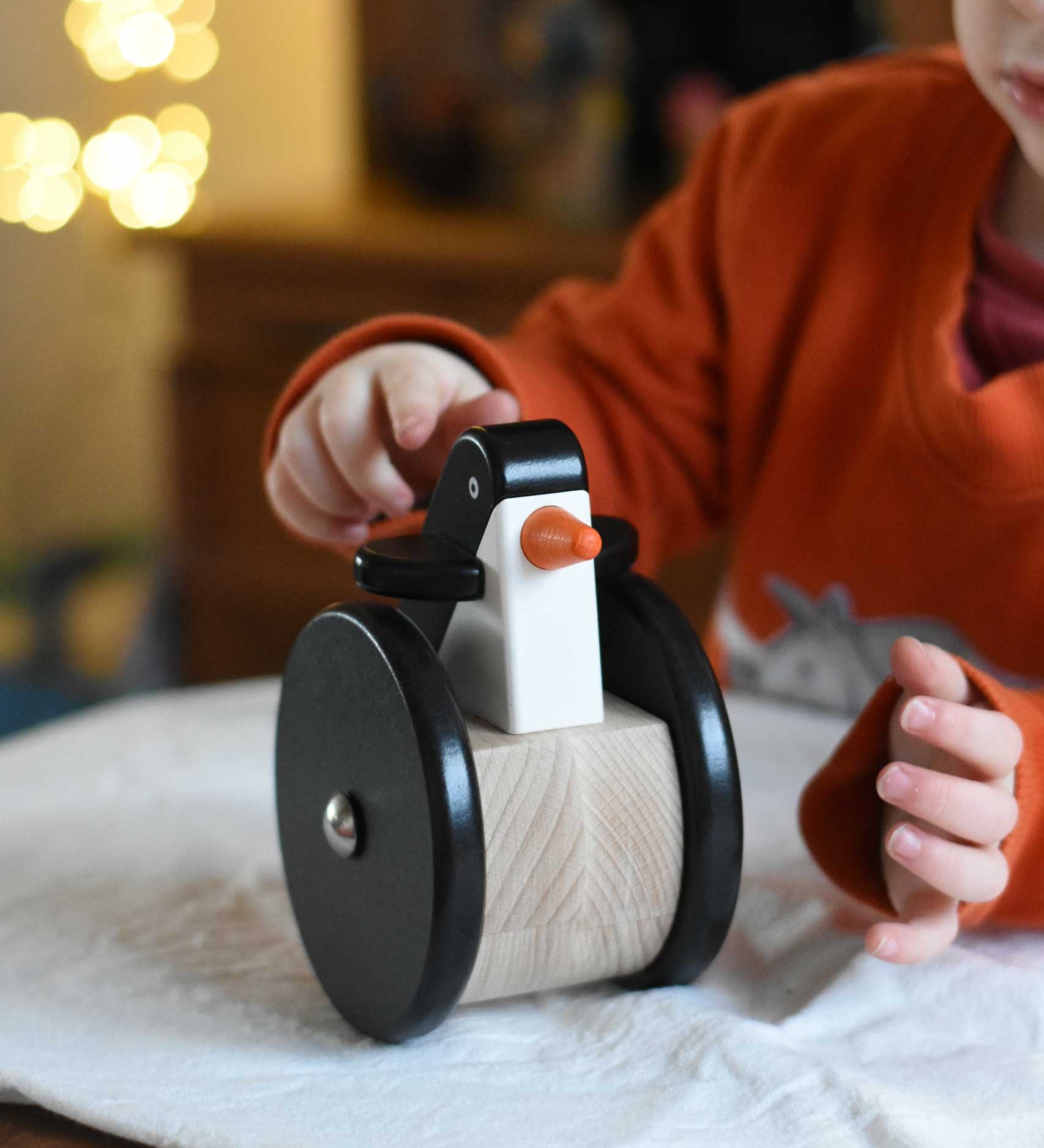 A child playing with the Bajo wobbling penguin push along wooden toy. This toy penguin has large black wheels. These heirloom quality toys by Bajo are part of a wide range of wooden toys available here at Babipur. 