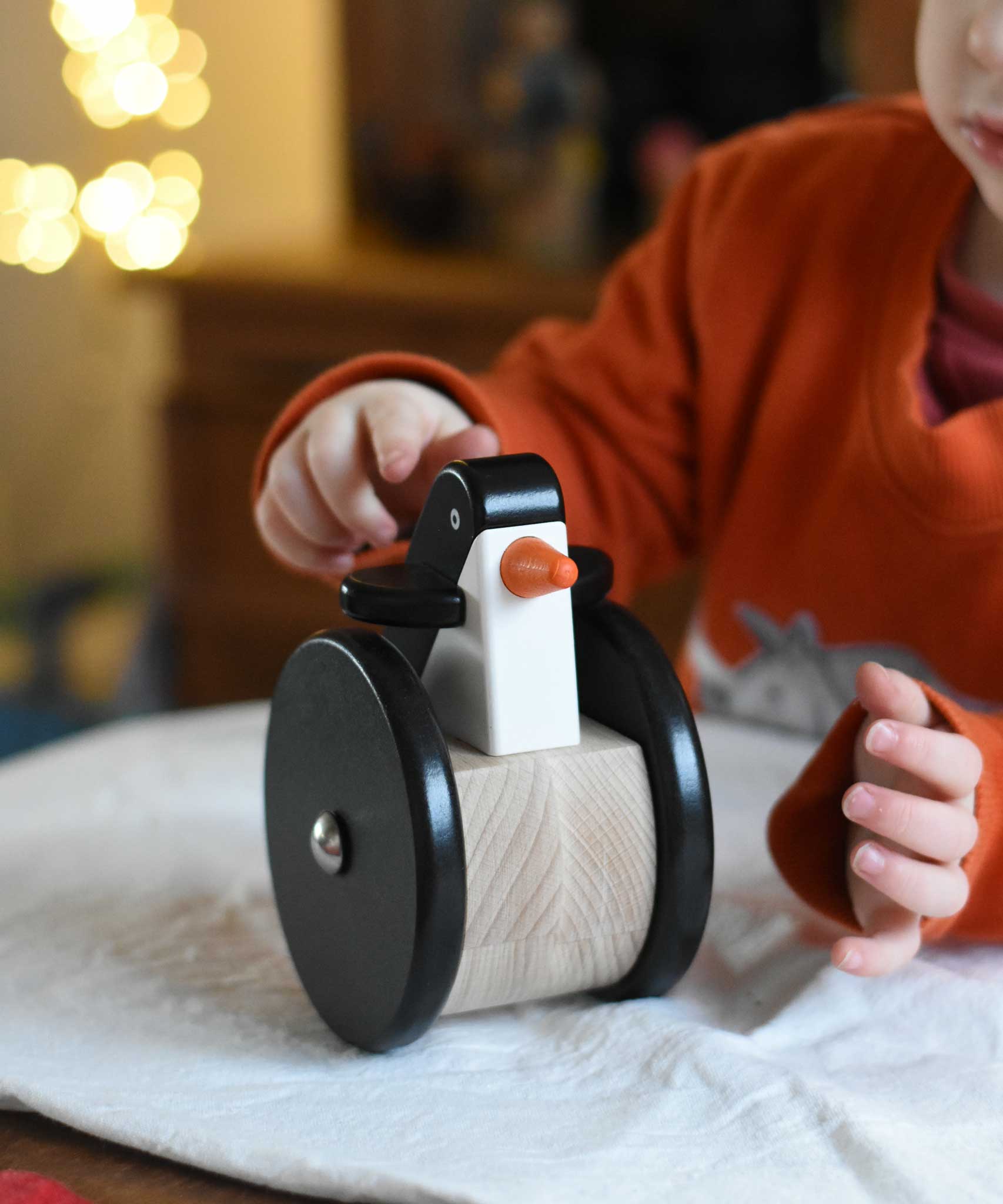 A child playing with the Bajo wobbling penguin push along wooden toy. This toy penguin has large black wheels. These heirloom quality toys by Bajo are part of a wide range of wooden toys available here at Babipur. 