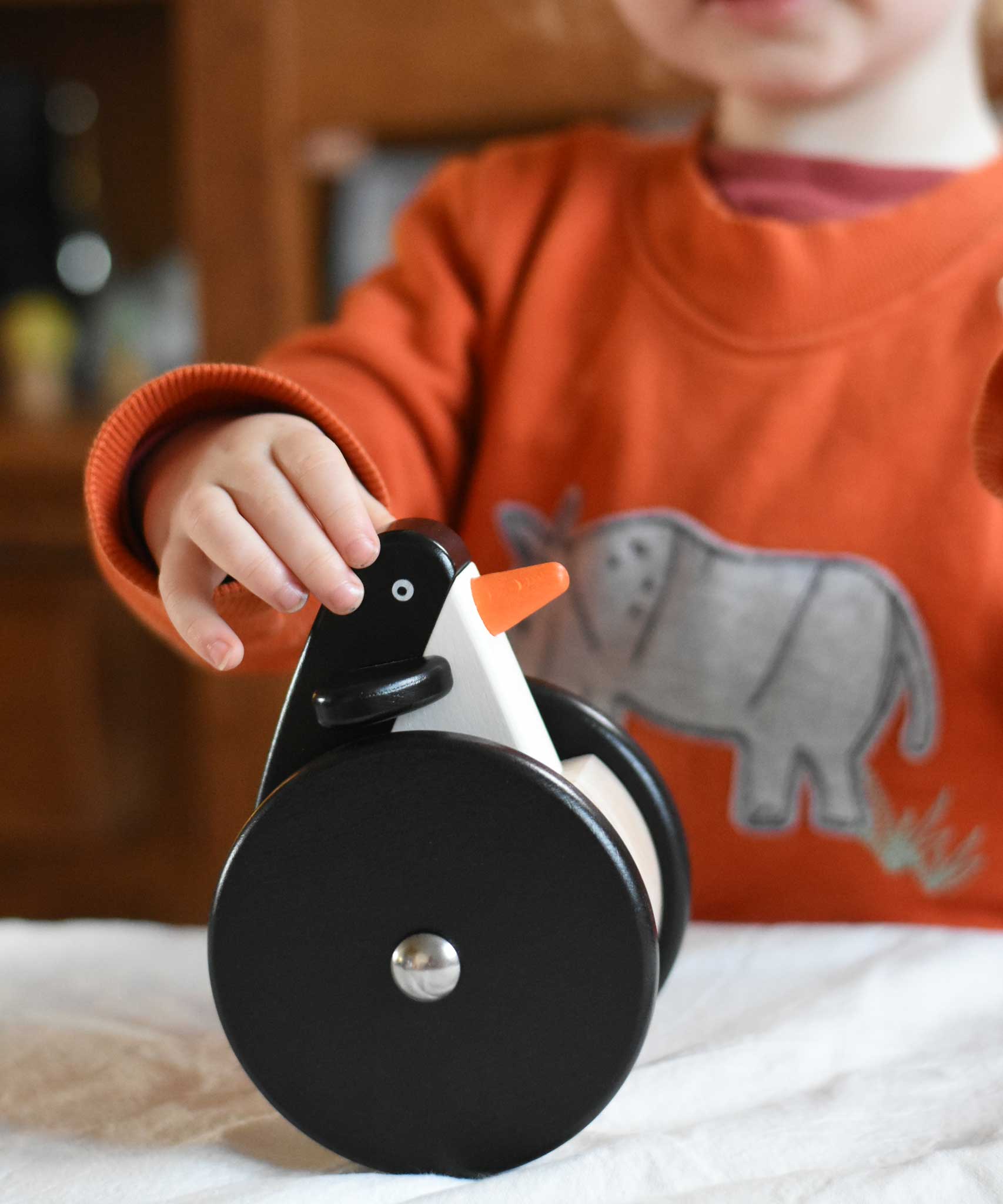 A child playing with the Bajo wobbling penguin push along wooden toy. This toy penguin has large black wheels. These heirloom quality toys by Bajo are part of a wide range of wooden toys available here at Babipur. 