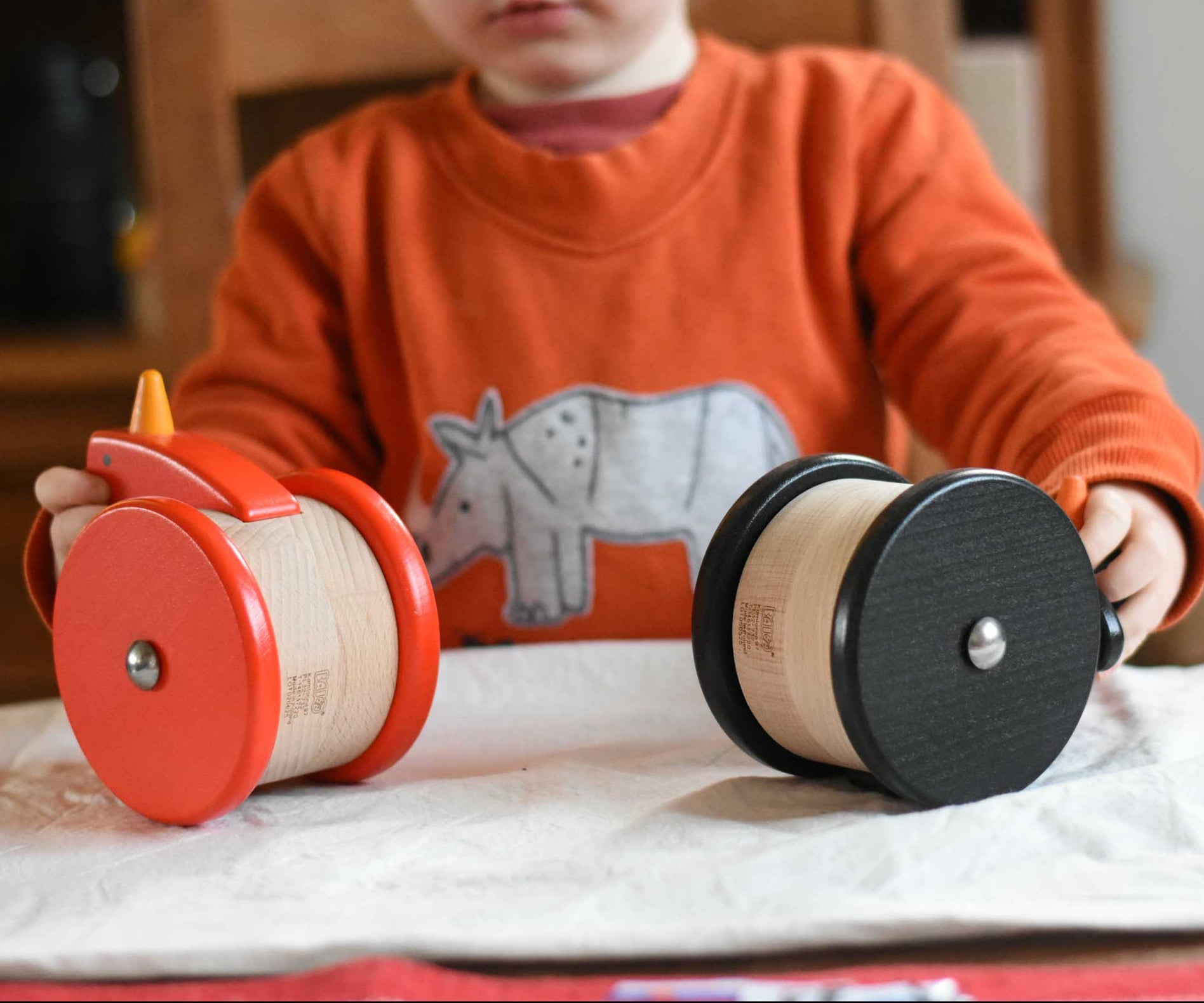 A child playing with the Bajo Red Wobbling Chicken and wobbling penguin toy. A red push along wooden chicken toy that bob up and down when pushed along.  These heirloom quality toys by Bajo are part of a wide range of wooden toys available here at Babipur.