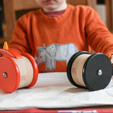 A child playing with the Bajo Red Wobbling Chicken and wobbling penguin toy. A red push along wooden chicken toy that bob up and down when pushed along.  These heirloom quality toys by Bajo are part of a wide range of wooden toys available here at Babipur.