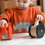 A child playing with the A child playing with the Bajo Red Wobbling Chicken and wobbling penguin toys. A red push along wooden chicken toy that bob up and down when pushed along.  These heirloom quality toys by Bajo are part of a wide range of wooden toys available here at Babipur.
