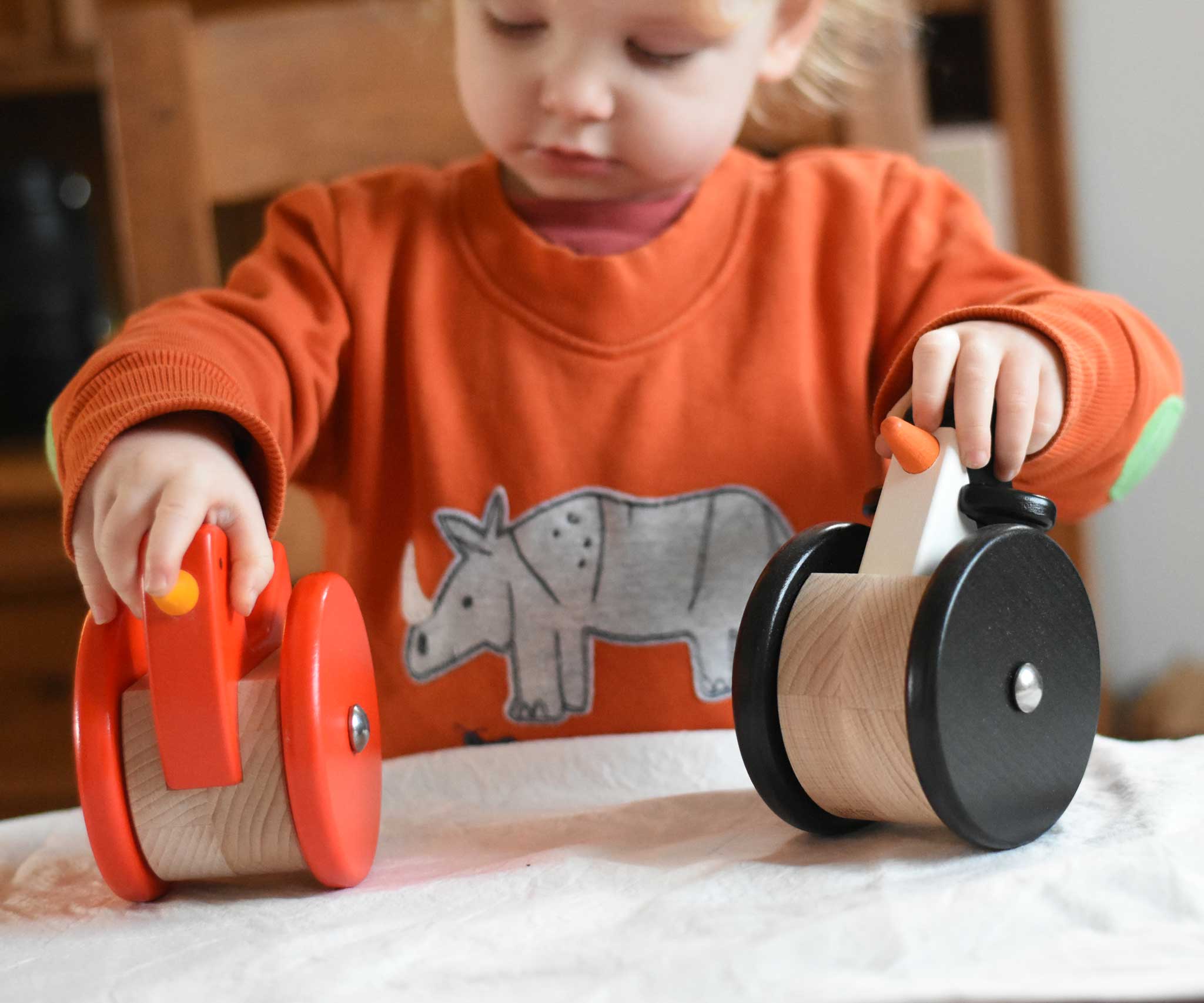 A child playing with the A child playing with the Bajo Red Wobbling Chicken and wobbling penguin toys. A red push along wooden chicken toy that bob up and down when pushed along.  These heirloom quality toys by Bajo are part of a wide range of wooden toys available here at Babipur.