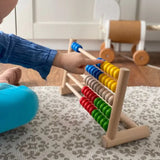 Child playing with Bajo's wooden 50 bead abacus in a playroom setting