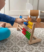 Child playing with Bajo's wooden 50 bead abacus in a playroom setting