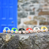 A group of Bajo hand made wooden yellow mini style cars available at Babipur standing on a stone wall