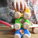 A stack of three Bajo mini wooden cars with a child's hand on the car on the top. These heirloom quality toys by Bajo are part of a wide range of wooden toys available here at Babipur. 