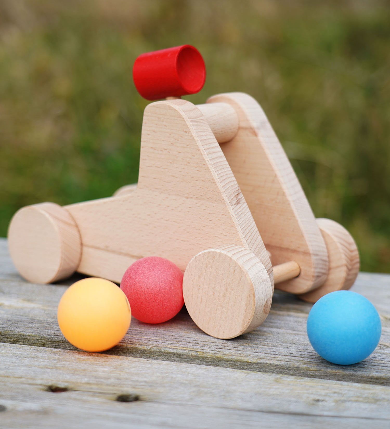 bajo catapult toy sitting on a wooden bench with balls around it