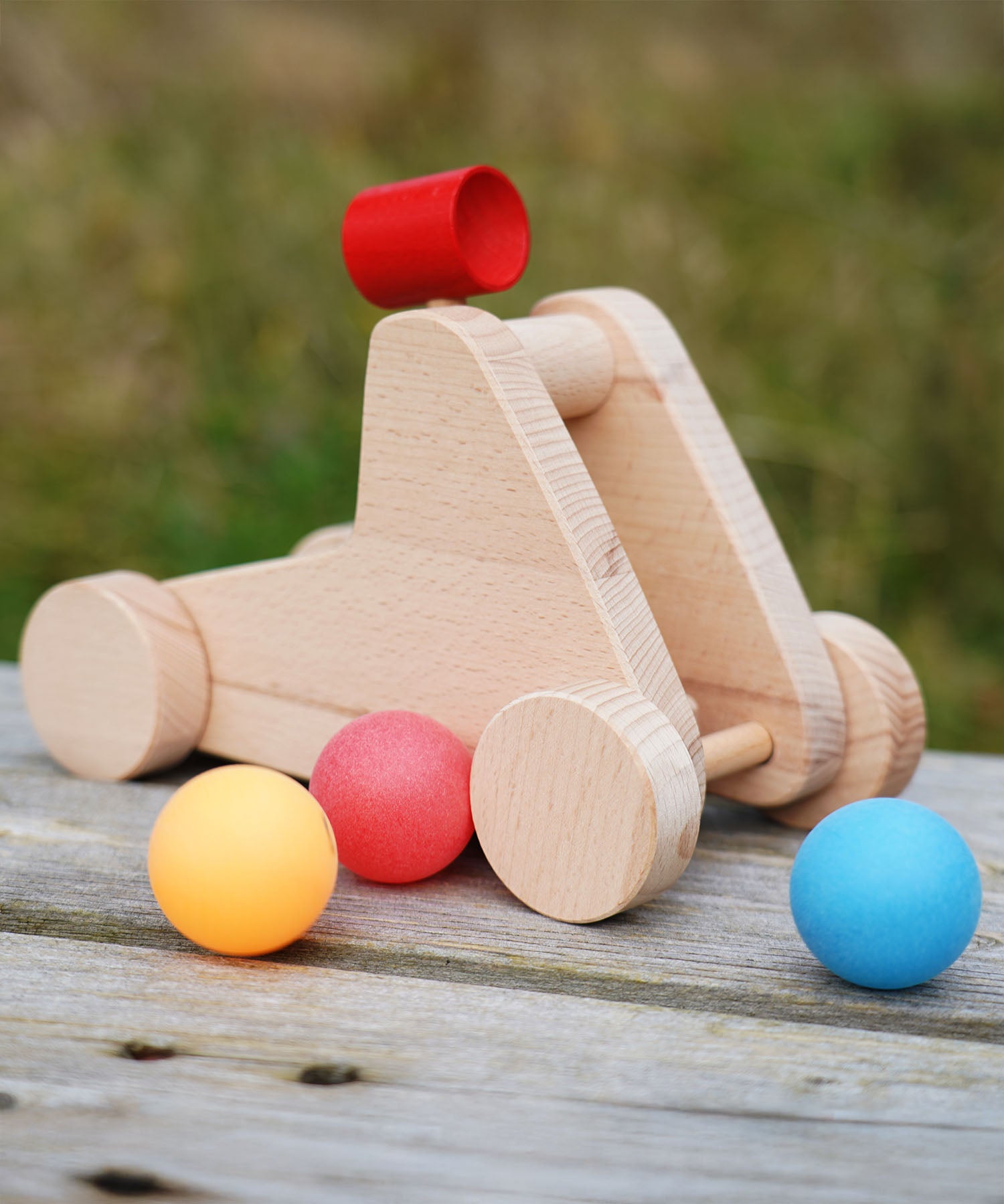 bajo catapult toy sitting on a wooden bench with balls around it