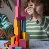Bajo 43 wooden building blocks. Child stacking blocks on wooden lid of box.