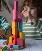 Bajo 43 wooden building blocks. Child stacking blocks on wooden lid of box.