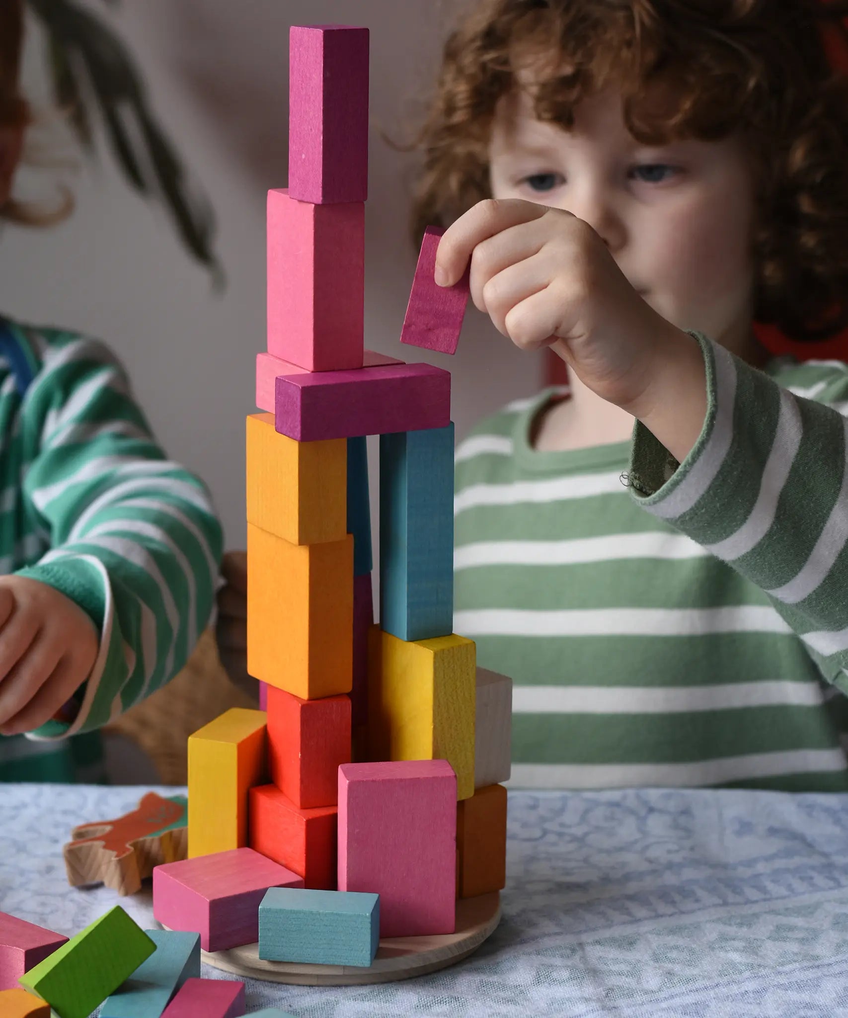 Bajo 43 wooden building blocks. Child stacking blocks on wooden lid of box.