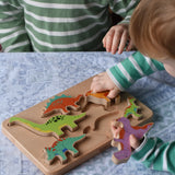 Bajo Wooden Dinosaur Puzzle with 6 colourful figures. Children placing the figures into the shaped slots on the base.