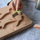 Bajo Wooden Dinosaur Puzzle. Child placing a figure into the shaped slot on the base.