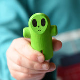 Close up of the green alien figure from the Bajo Flying Saucer set in a child's hand.