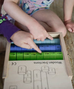 Children pointing at different coloured wooden disks from the Bajo fraction set showing their fractions painted in black