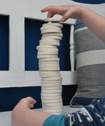 A close up of a child's hand stacking the wooden dics from a Bajo Memory Game on top of each other. These heirloom quality toys by Bajo are part of a wide range of wooden toys available here at Babipur.