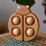 Bajo natural wooden ladybird teether  placed on a rattan stool in the Babipur playroom.