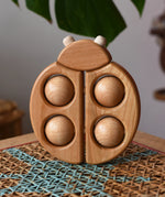 Bajo natural wooden ladybird teether  placed on a rattan stool in the Babipur playroom.