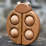Bajo natural wooden ladybird teether placed on a stone wall outdoors in the Babipur garden.
