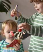 Bajo magnetic fishing game toy. Child holding wooden rod with black fish attached.