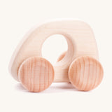 A Bajo handmade wooden natural mini car available at Babipur. Features matching unpainted wheels and a cut out hole for a easy hold. Photo is in a playroom setting