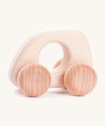 A Bajo handmade wooden natural mini car available at Babipur. Features matching unpainted wheels and a cut out hole for a easy hold. Photo is in a playroom setting