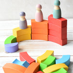 Grimm's figures stood on top of the Bajo plastic-free stacking wooden rainbow blocks