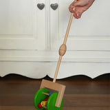 Bajo push along wooden toy rattle in a child's hand. Green rollers with coloured pieces in the middle attacked to a stick.