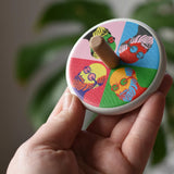 Bajo Pop Art Mr Bajor Spinning Top in an adult's hand showing the design on the top.