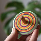 Bajo Colourful Circles Spinning Top in an adult's hand showing the design on the top.